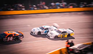 Car with BKFC branding racing against other cars