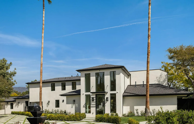 Beautiful white stucco home with black roof and two tall palm trees at 320 Patrician Way in Pasadena, California